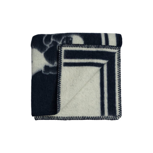 Sau Blått Halvpledd fra Snekkerbua, et stilfullt ullpledd i blått. Den perfekte kombinasjonen av varme og eleganse, ideell for koselige kvelder hjemme eller som et dekorativt element i stuen.