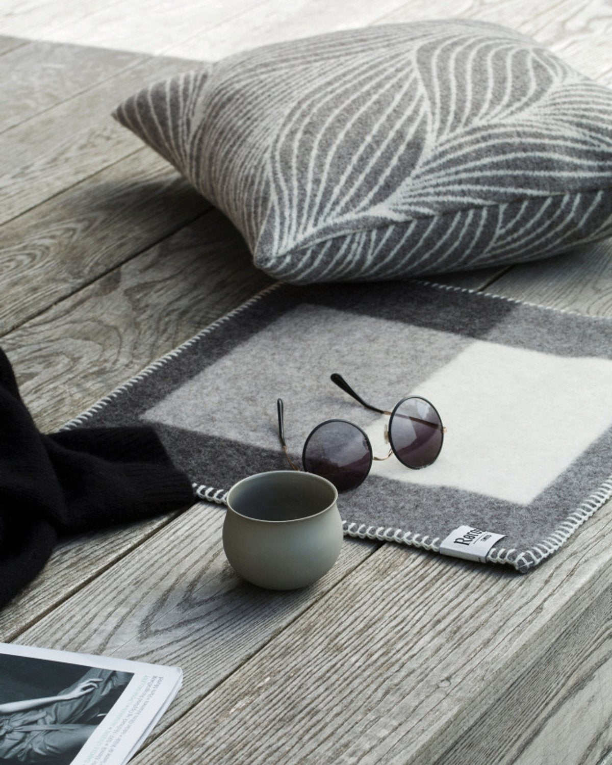 Syndin Slate sitteunderlag fra Røros Tweed, et slitesterkt og komfortabelt underlag laget av høy kvalitets ull, perfekt for utendørs aktiviteter og å holde deg varm på kalde dager.