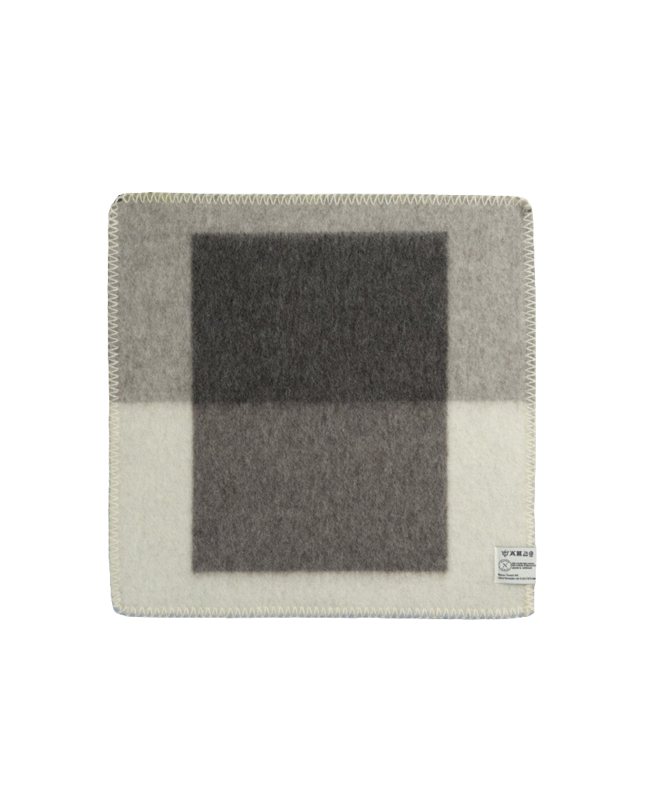 Syndin Slate sitteunderlag fra Røros Tweed, et slitesterkt og komfortabelt underlag laget av høy kvalitets ull, perfekt for utendørs aktiviteter og å holde deg varm på kalde dager.