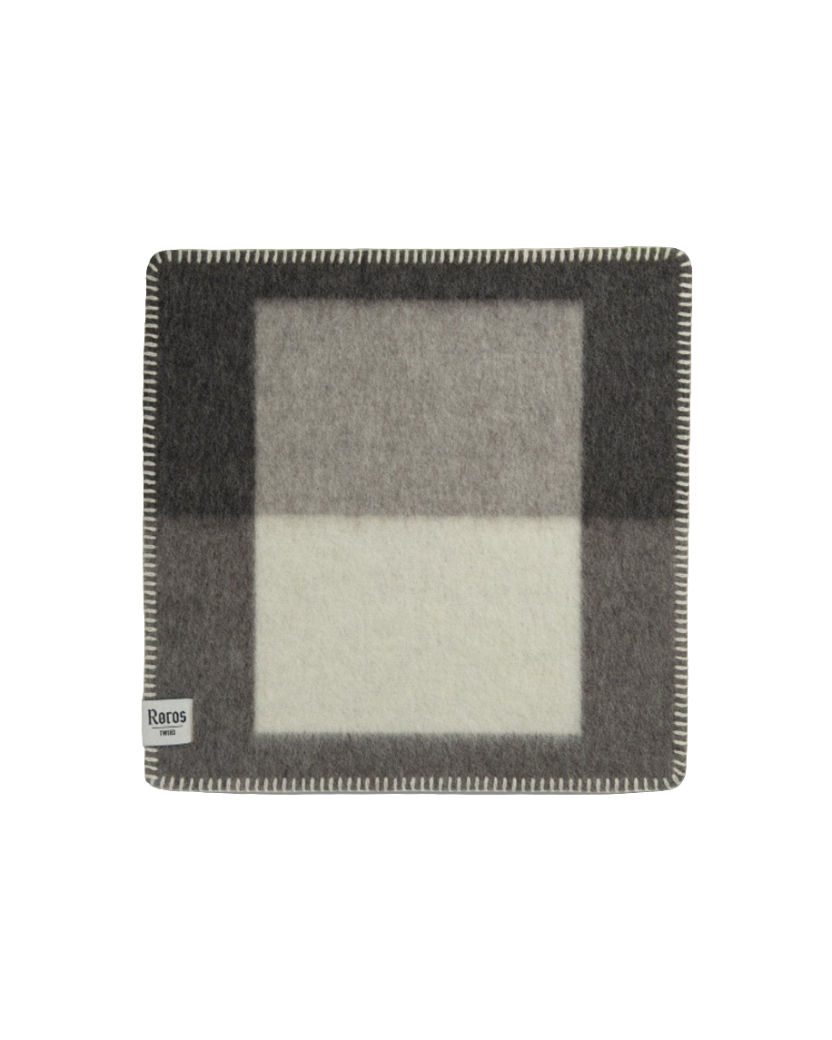 Syndin Slate sitteunderlag fra Røros Tweed, et slitesterkt og komfortabelt underlag laget av høy kvalitets ull, perfekt for utendørs aktiviteter og å holde deg varm på kalde dager.