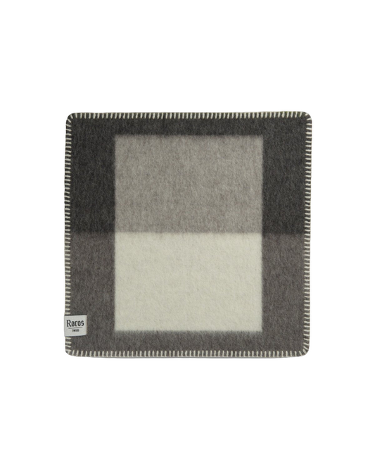 Syndin Slate sitteunderlag fra Røros Tweed, et slitesterkt og komfortabelt underlag laget av høy kvalitets ull, perfekt for utendørs aktiviteter og å holde deg varm på kalde dager.