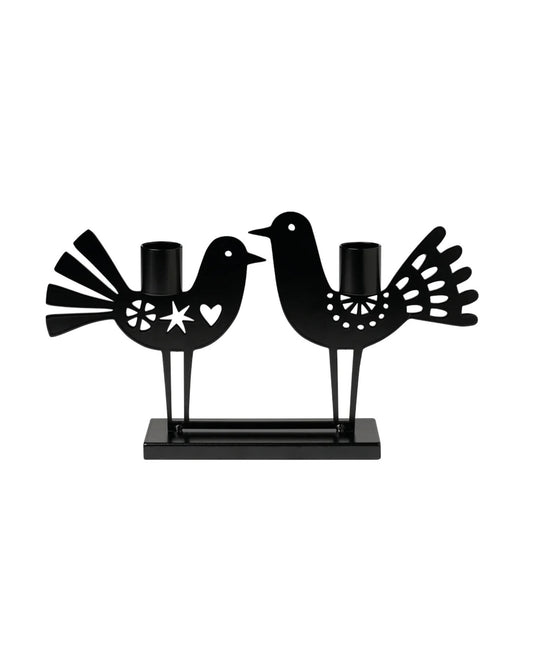Two Birds jernlysestake fra Snekkerbua. Denne vakre lysestaken er laget av solid smijern, og har et delikat design med to fugler i stilisert form. Perfekt for å skape en koselig atmosfære i hjemmet, enten som borddekorasjon eller på en hylle. Lysestaken gir et klassisk, tidløst preg og passer inn i både moderne og tradisjonelle interiørstiler. En ideell gave til de som setter pris på detaljerte, håndlagde produkter.