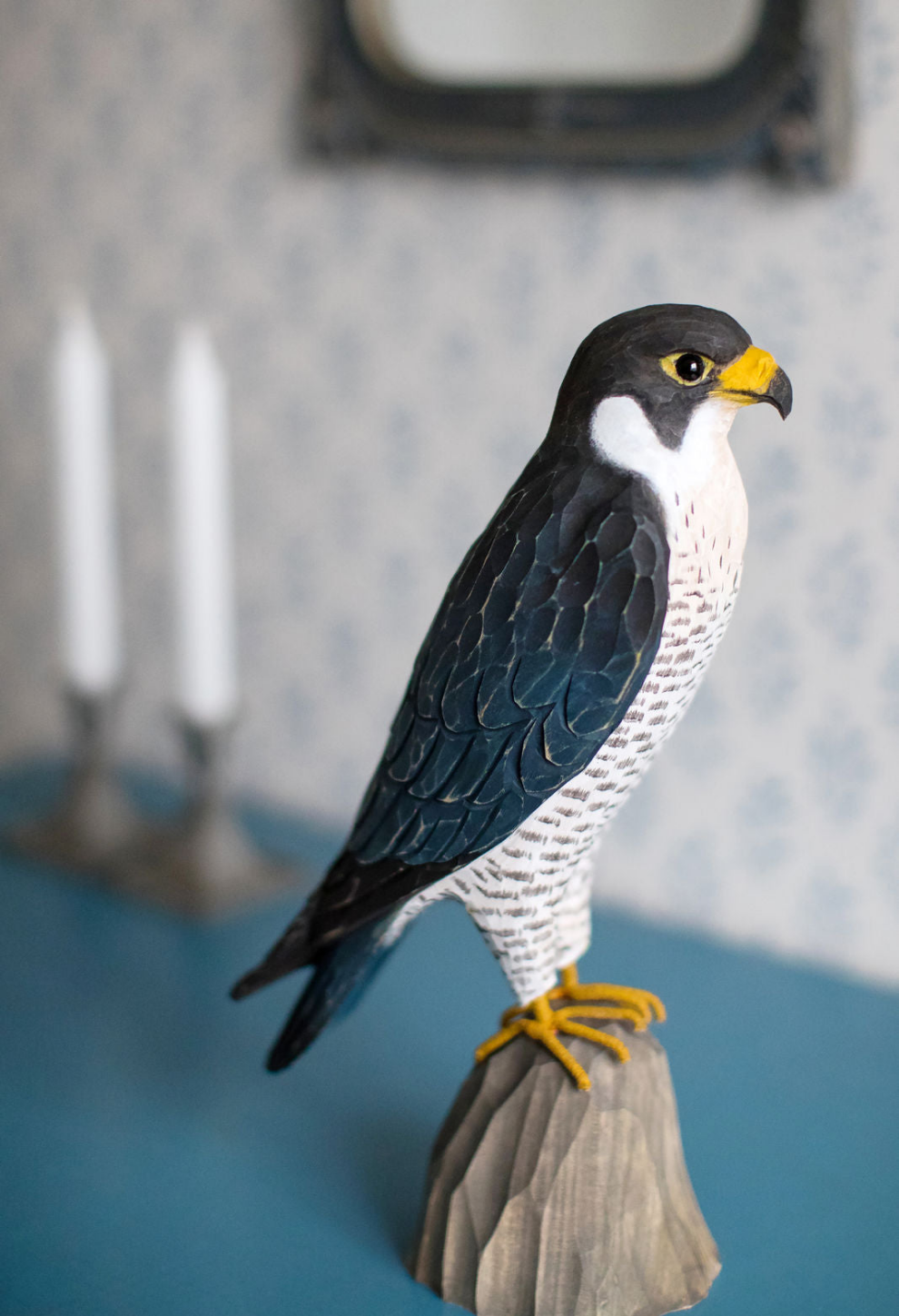 Vandrefalk - Trefugl fra Snekkerbua. Denne detaljrike og vakre treskulpturen av en vandrefalk er laget for å fange essensen av denne imponerende rovfuglen. Perfekt som en dekorativ detalj i hjemmet eller som en gave til naturinteresserte. Trefuglen er laget av kvalitetsmateriale og har et naturlig, rustikk utseende som fremhever både håndverk og naturens skjønnhet.